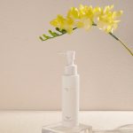 Minimalist skincare product display with yellow flowers on a white backdrop.