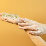 Hands covered in foamy soap, representing hygiene and cleanliness against a vibrant yellow background.